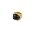 A gold ring featuring a large, polished dark blue oval stone, set in a textured, organic-shaped gold band, shown on a plain white background.
